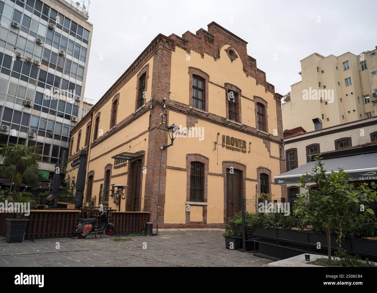 Un affascinante edificio storico in mattoni con una facciata rustica gialla, caratterizzato da finestre ad arco e uno stile architettonico retrò. L'edificio ospita il Rov Foto Stock