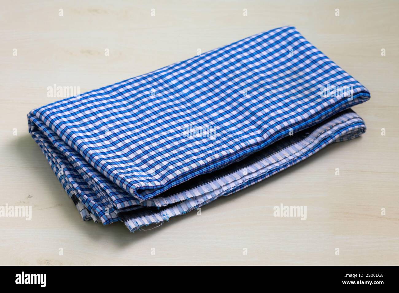 Lungi in cotone piegato, un tradizionale indumento da uomo nell'Asia meridionale, esposto su una superficie in legno. Un simbolo della moda e dello stile di vita del Bangladesh. Foto Stock