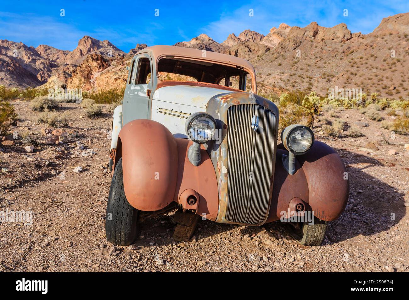 Una vecchia macchina è parcheggiata su una strada rocciosa. L'auto è arrugginita e ha un lavoro di verniciatura sbiadito. La scena è desolata e silenziosa, senza altre auto o persone in si Foto Stock