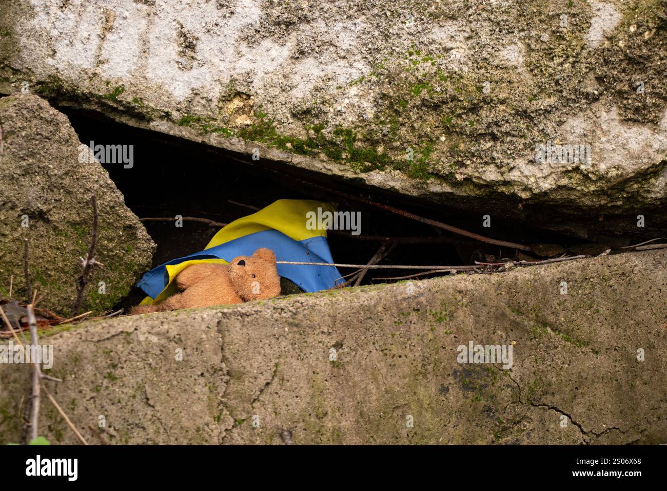 Orsacchiotto marrone per bambini e bandiera Ucraina sotto le macerie in Ucraina, guerra Foto Stock