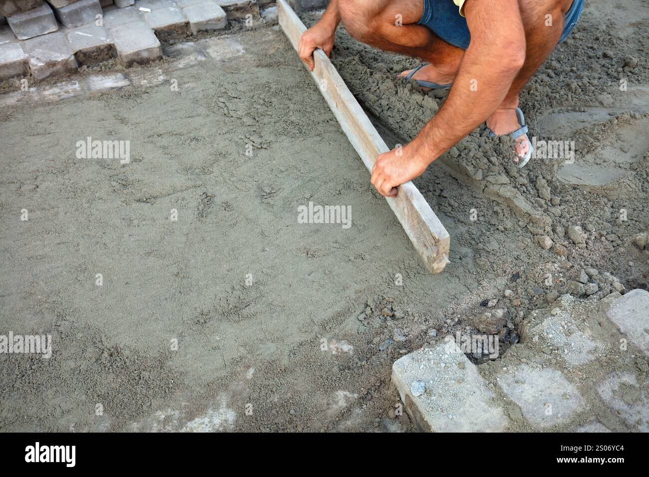 I pavimenti realizzati a mano prendono forma sotto mani esperte in un pomeriggio di sole. Copia spazio. Foto Stock
