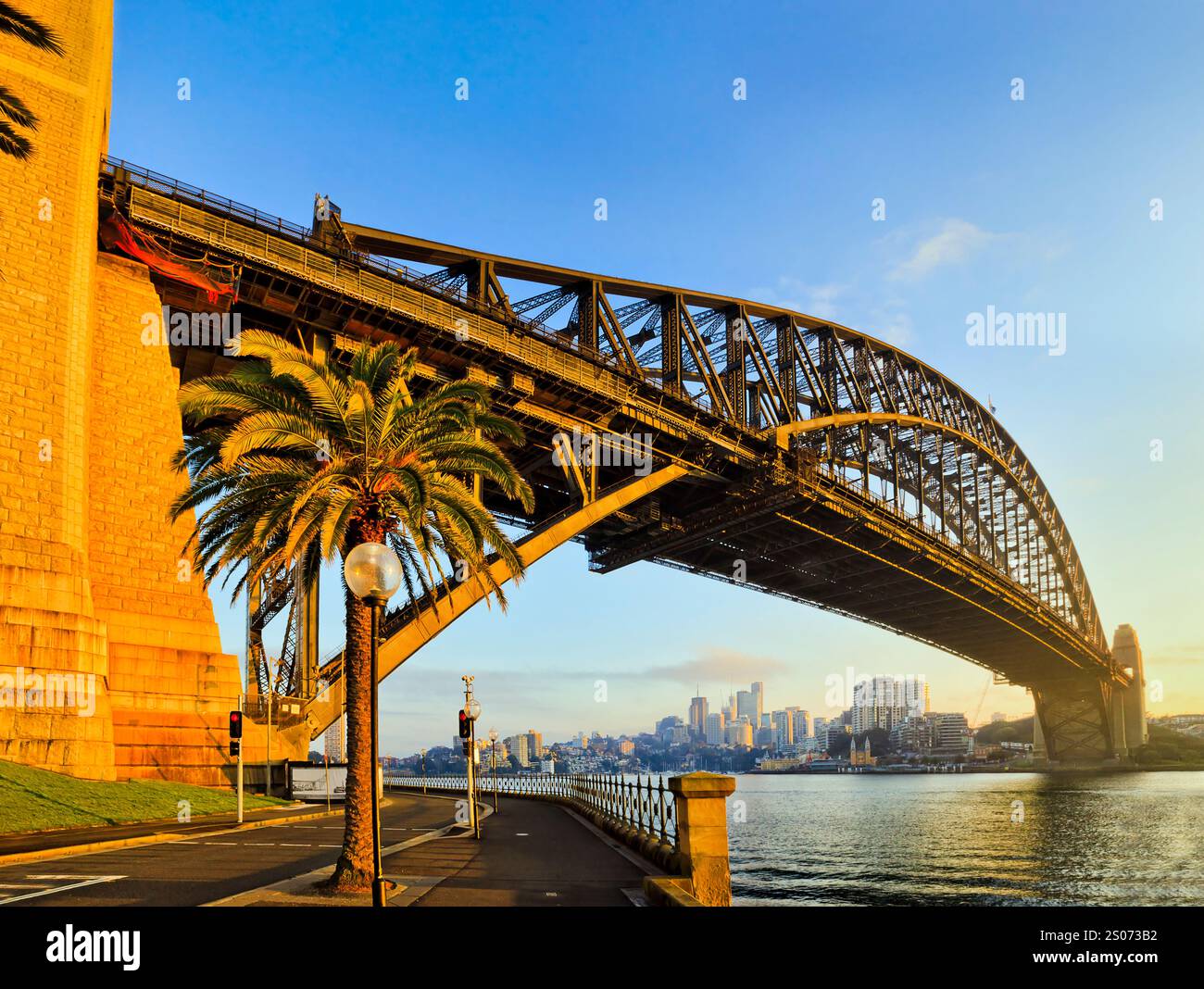 Enorme arco in acciaio del ponte del porto di Sydney dalle rocce sul porto di Sydney con luce soffusa del mattino. Foto Stock