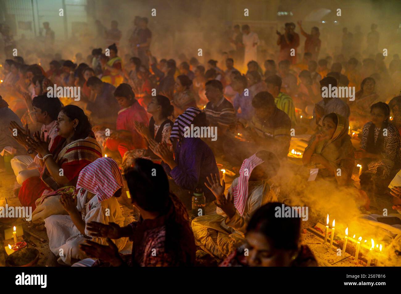 I devoti si siedono in preghiera con incenso acceso e lampade a olio incandescenti durante Rakher Upobash, una festa sacra del digiuno, all'Ashram i di Lokenath Brahmachari Foto Stock