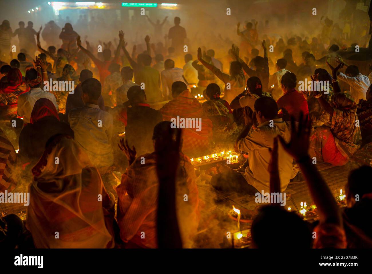 I devoti si siedono in preghiera con incenso acceso e lampade a olio incandescenti durante Rakher Upobash, una festa sacra del digiuno, all'Ashram i di Lokenath Brahmachari Foto Stock