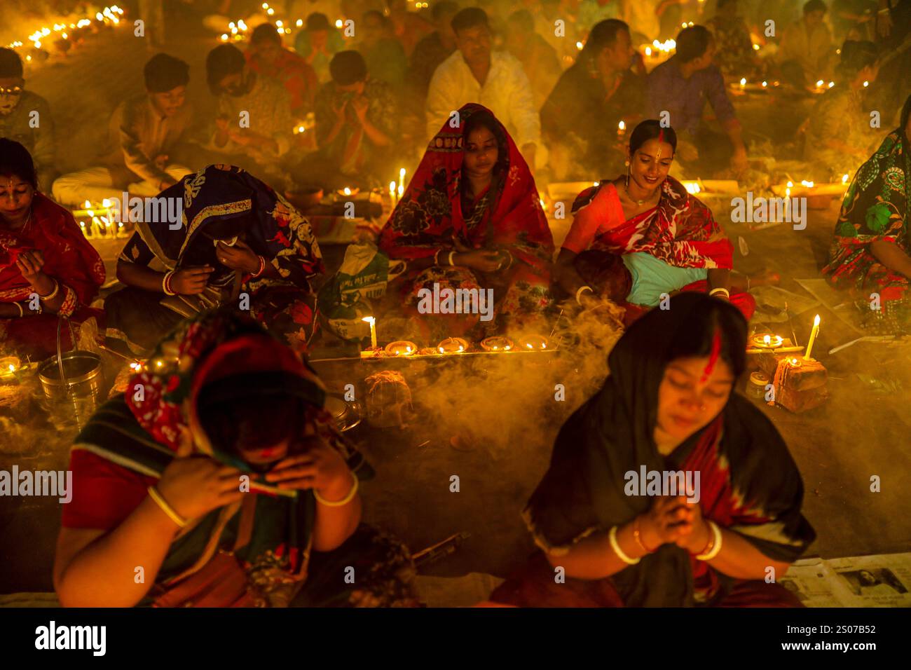 I devoti si siedono in preghiera con incenso acceso e lampade a olio incandescenti durante Rakher Upobash, una festa sacra del digiuno, all'Ashram i di Lokenath Brahmachari Foto Stock