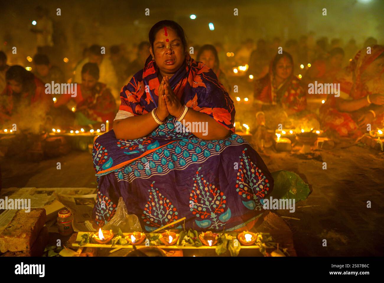 I devoti si siedono in preghiera con incenso acceso e lampade a olio incandescenti durante Rakher Upobash, una festa sacra del digiuno, all'Ashram i di Lokenath Brahmachari Foto Stock