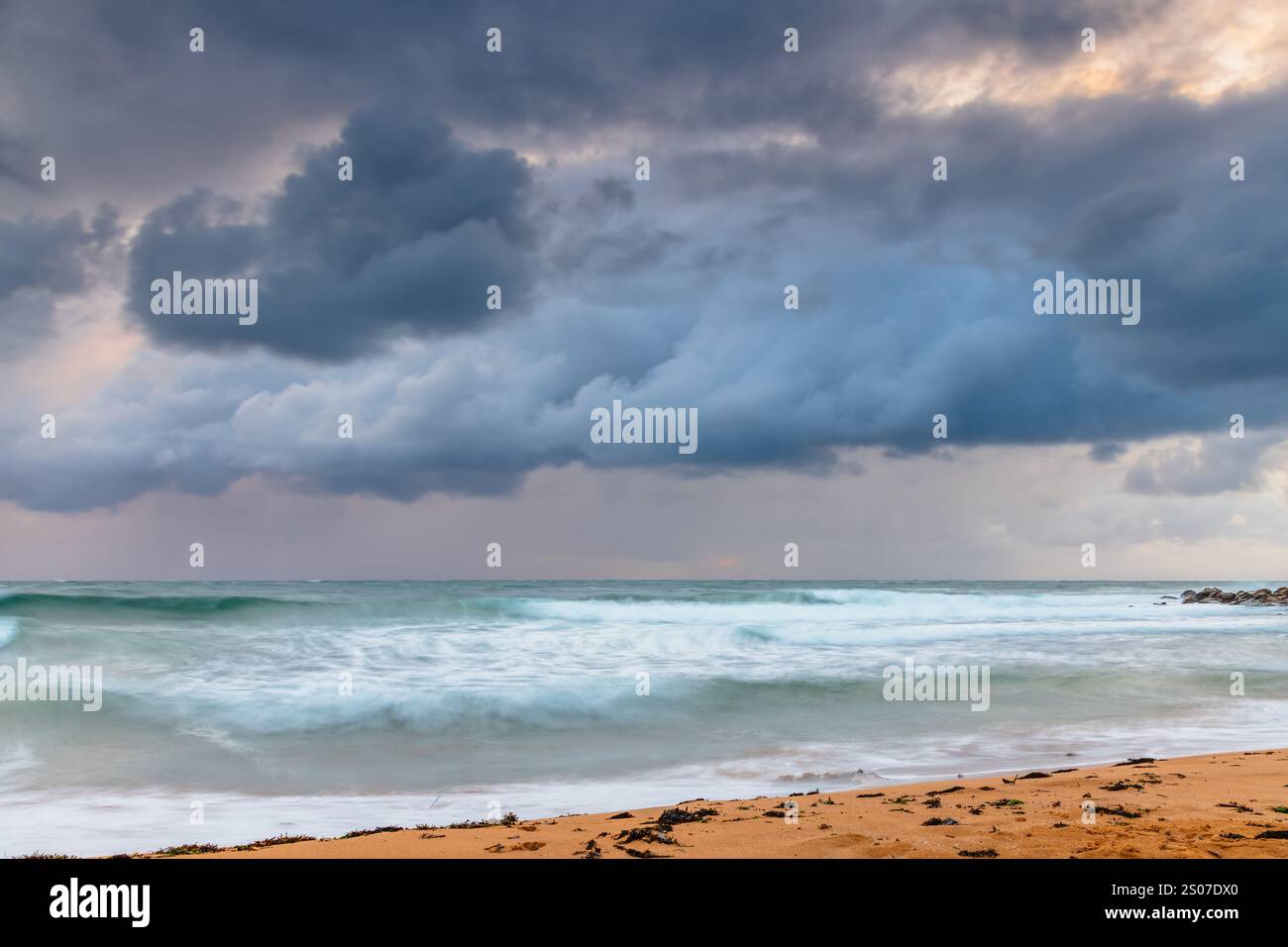 Alba di giorno piovoso con cielo coperto e onde instabili di buone dimensioni a Macmasters Beach sulla Central Coast, NSW, Australia. Foto Stock