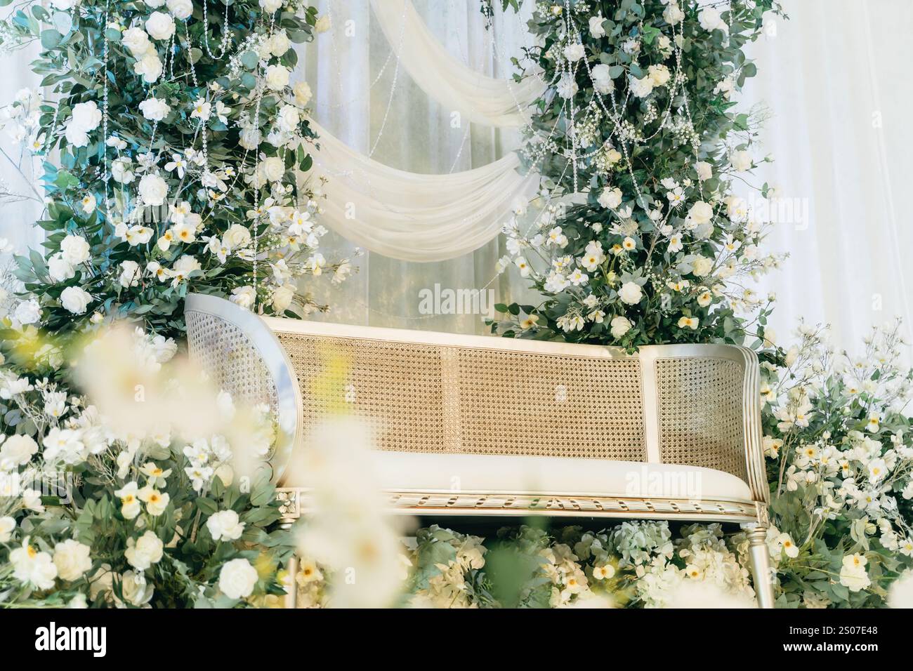 Elegante sfondo per matrimoni floreali con lussuoso divano, rose bianche, verde e ghirlande di cristallo - perfetto per matrimoni ed eventi speciali Foto Stock