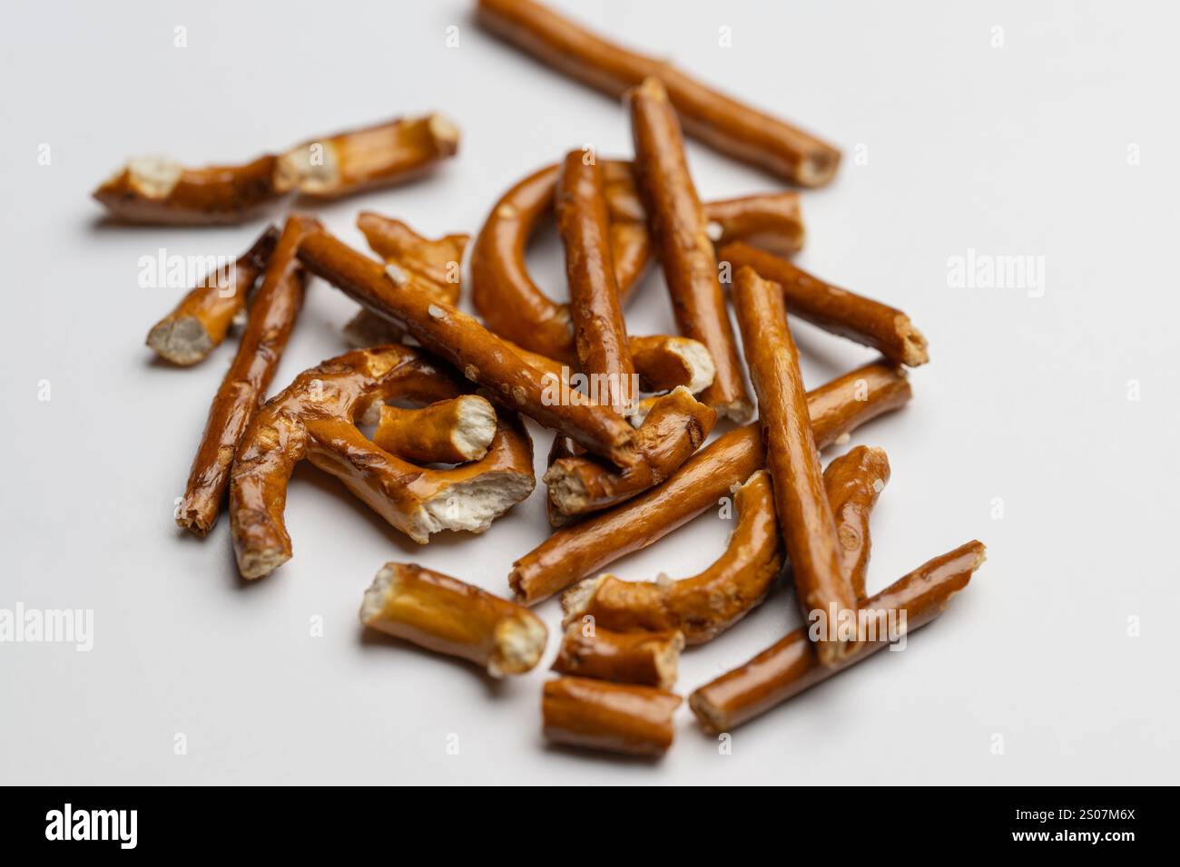 , Deutschland, 26.12.2024, Nahaufnahme von zerbrochenen Salzstangen, unregelmäßig auf einem Weißen Hintergrund verteilt. Perfektes Motiv für snack u Foto Stock