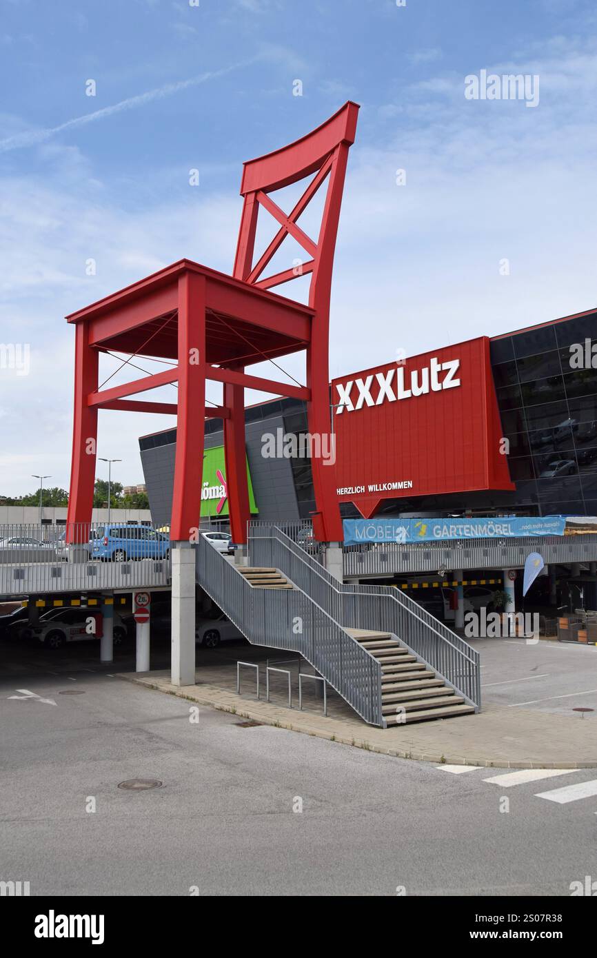 Sedia gigante rossa fuori dal negozio di mobili XXXLutz GMBH a Vienna, Austria, giugno 2024 Foto Stock