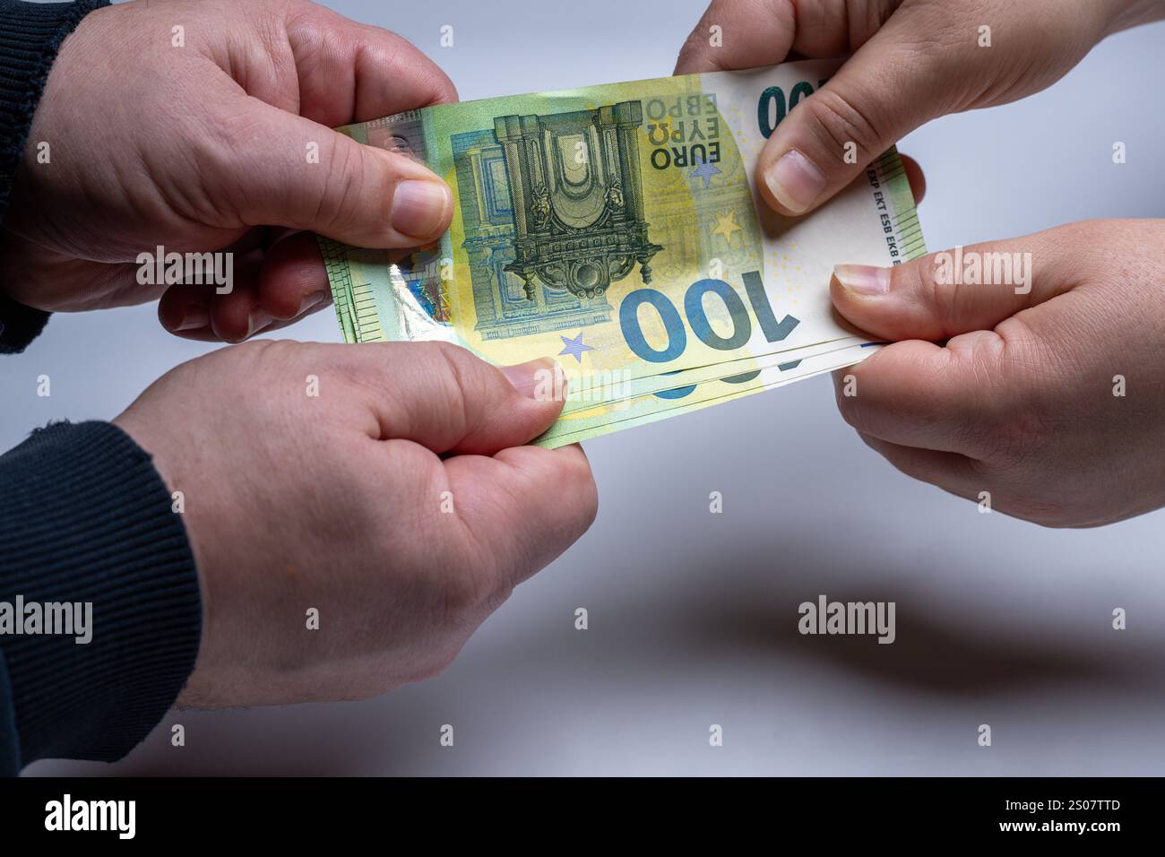 , Deutschland, 26.12.2024, Nahaufnahme von zwei Händen, die um einen 100-Euro-Schein ringen. Symbol für Geldstreit, finanzielle Konflikte oder Zahlun Foto Stock