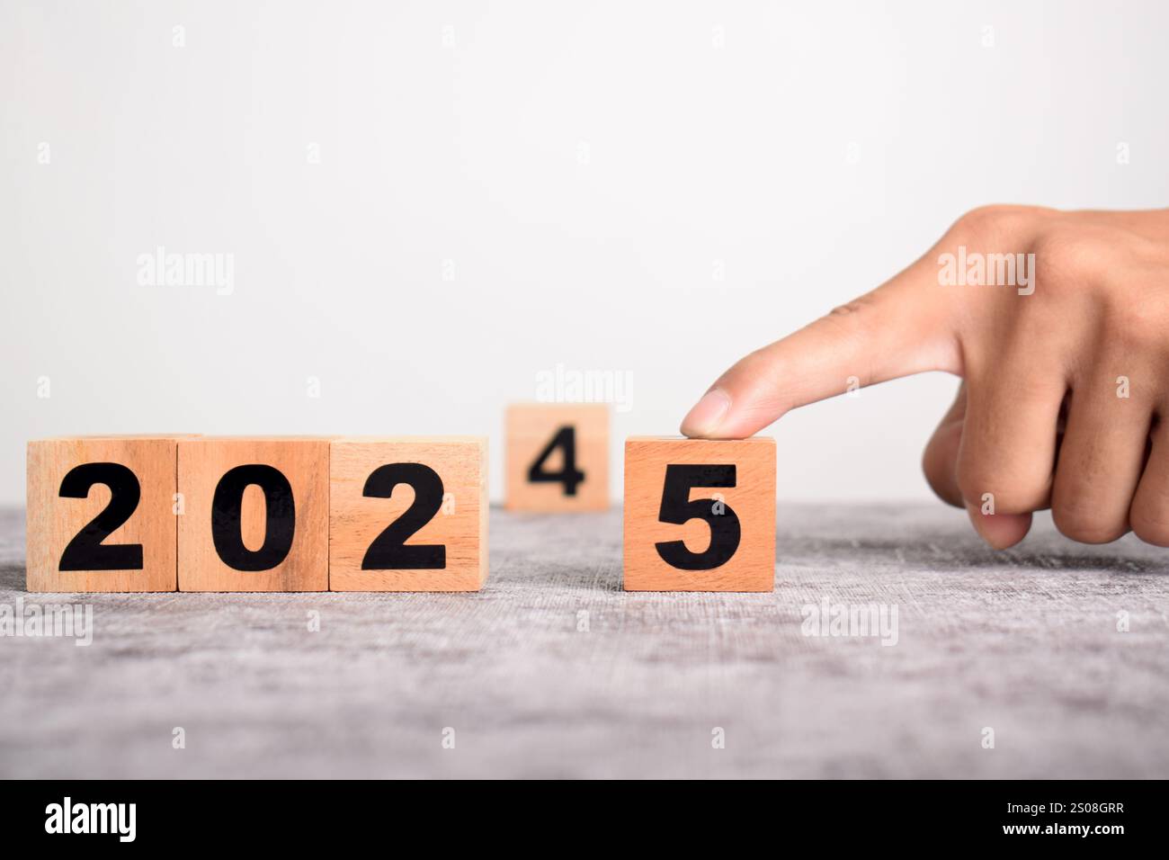 Una mano sostituisce 2024 con 2025 utilizzando blocchi cubici di legno. Pianificazione aziendale e conto alla rovescia fino al 2025 Foto Stock