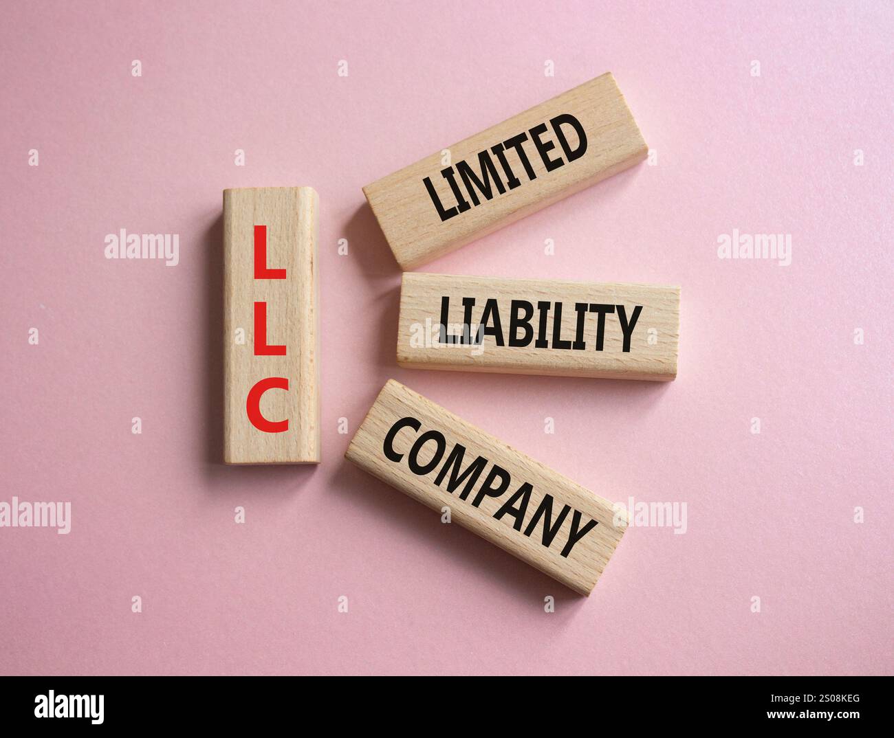LLC - società a responsabilità limitata. Cubi in legno con parola LLC. Bellissimo sfondo rosa. Business e LLC. Copia spazio. Foto Stock