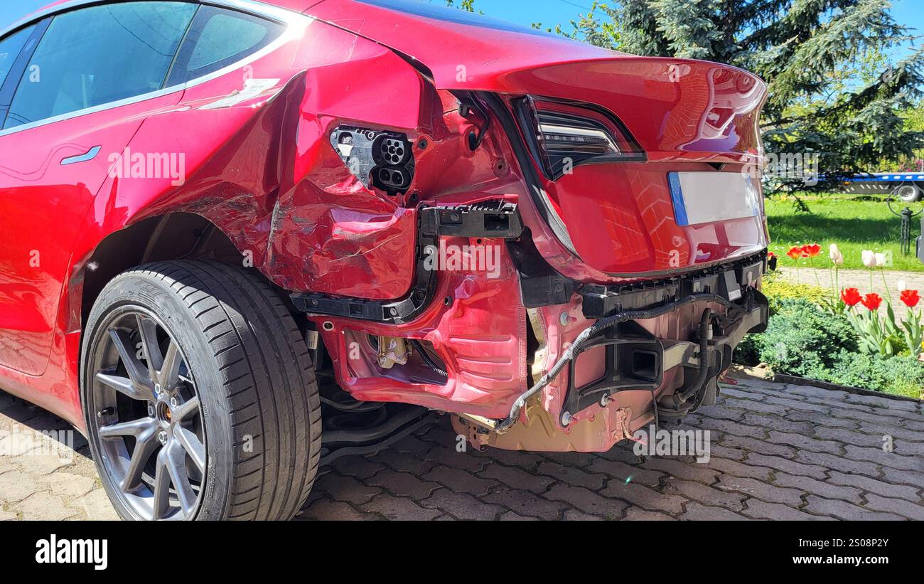 Vista ravvicinata dei danni alla vettura rossa dopo un incidente grave: Parti danneggiate, metallo deformato, elementi strappati Foto Stock