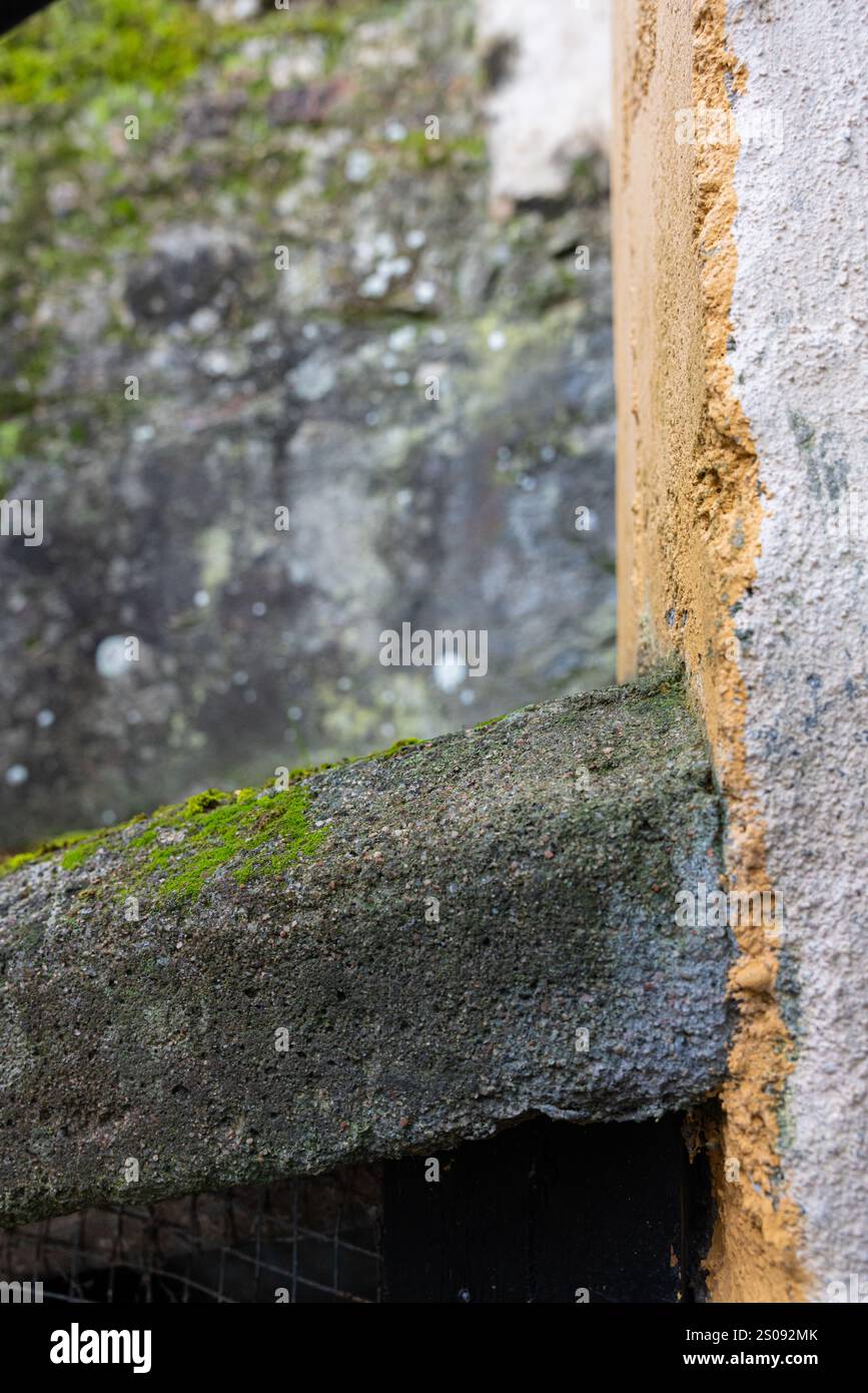 Dettagli dell'angolo su un muro. La parete è realizzata in cemento e parte è dipinta di giallo. Immagine per gli sfondi Foto Stock