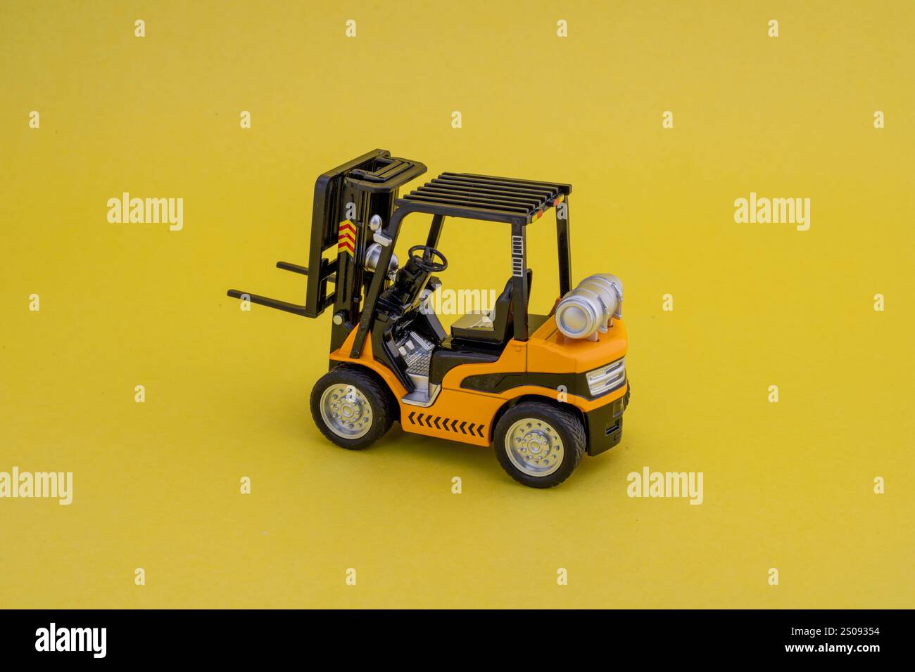 Giocattolo per carrelli elevatori giallo in miniatura su sfondo giallo con spazio per le copie. Foto Stock