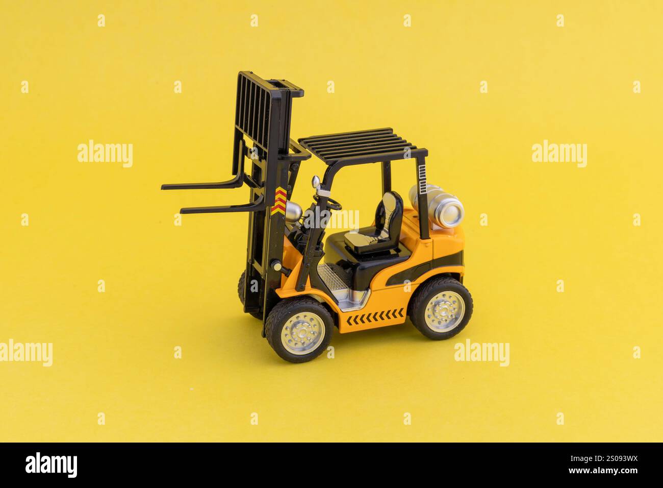 Caricatore per carrello elevatore giocattolo con elevatore sollevato su sfondo giallo. Copia spazio per il testo. Foto Stock