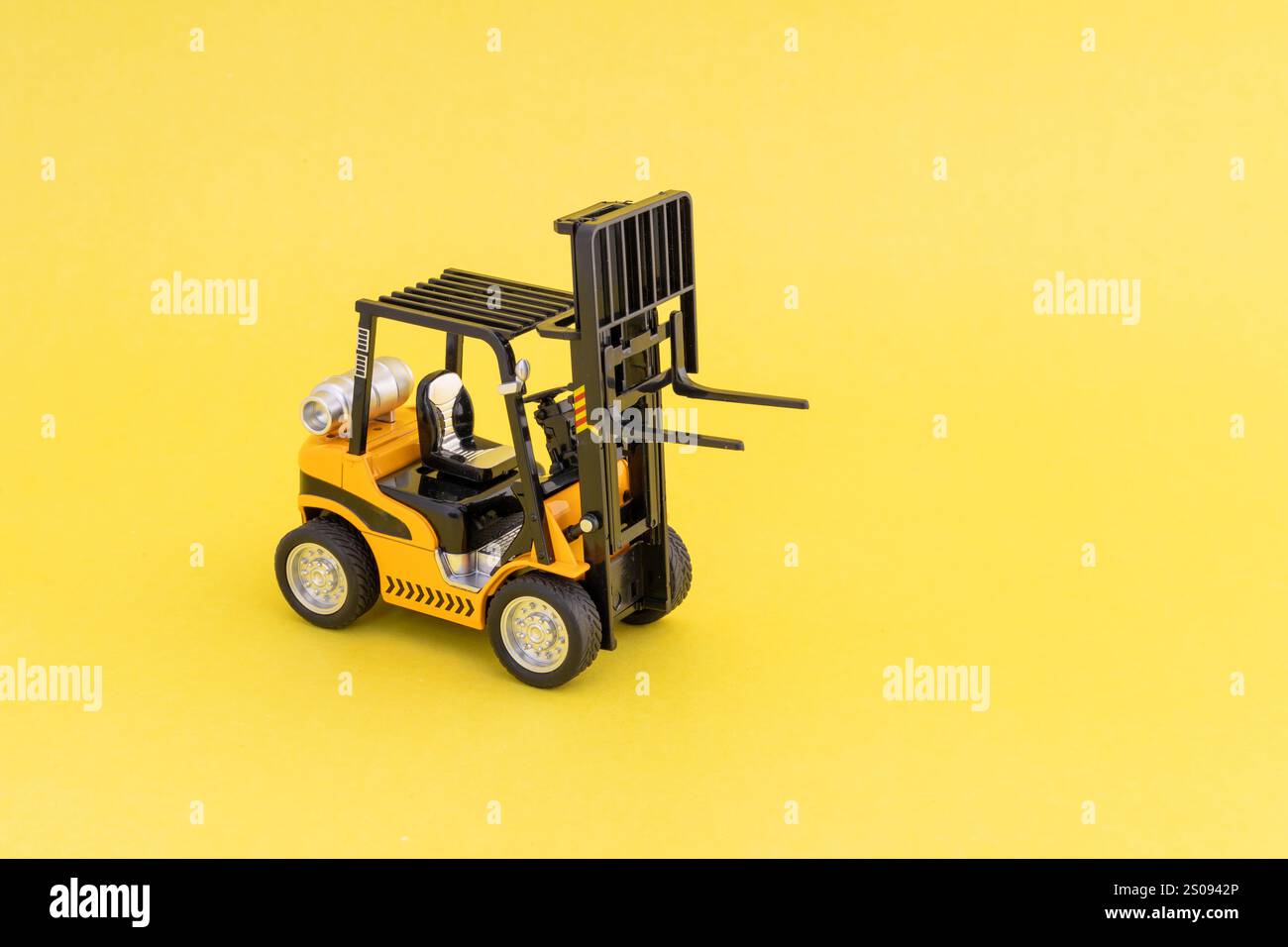 Carrello elevatore giocattolo giallo su sfondo giallo con spazio vuoto per il testo. Foto Stock