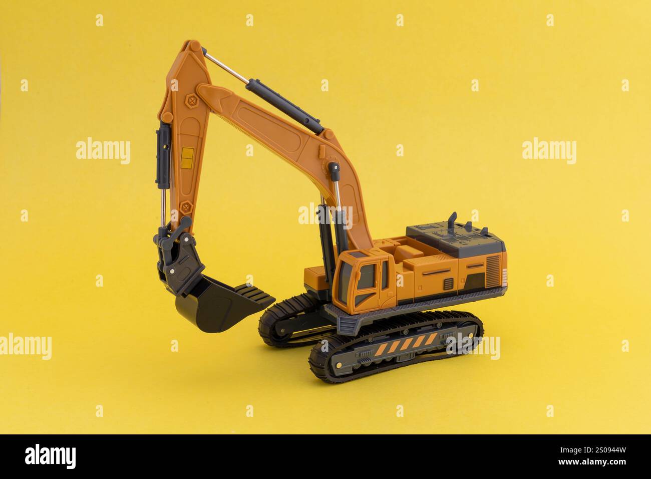 Modello in scala da escavatore miniaturizzato su sfondo giallo Foto Stock
