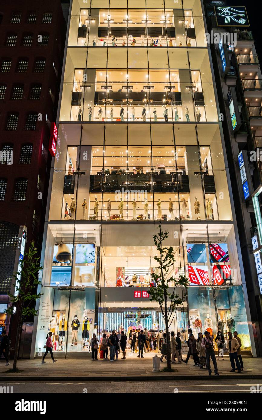 La facciata in vetro luminoso del negozio di punta Ginza uni Qlo. Vista frontale dell'edificio a otto piani, con il suo ingresso affollato di amanti dello shopping. Foto Stock