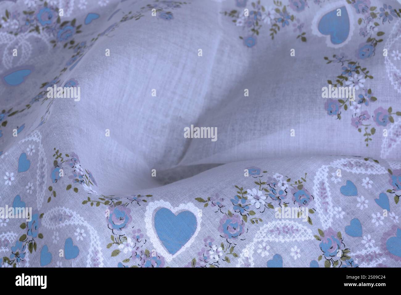 Cuori e fiori su tessuto fazzoletto tenue mostrano un design delicato per il testo centrale. Il panno Valentine è un tessuto di cotone di lino fine. Il motivo floreale è blu. Foto Stock