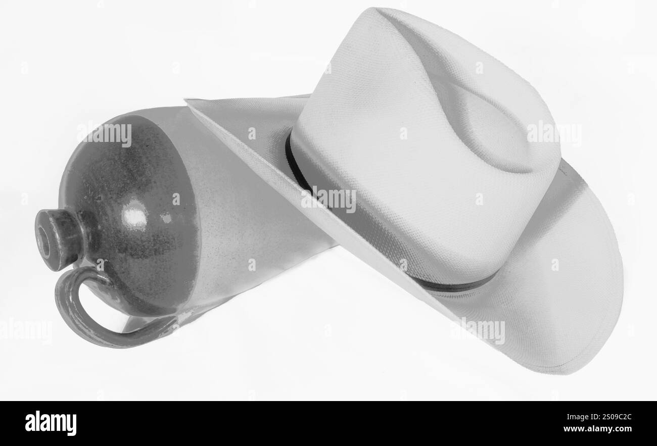 L'immagine in bianco e nero mostra un cappello di paglia da cowboy e una caraffa vuota per whisky che riposano insieme. I soggetti a forma di triangolo indicano che il giorno è finito e il tempo per uscire. Foto Stock