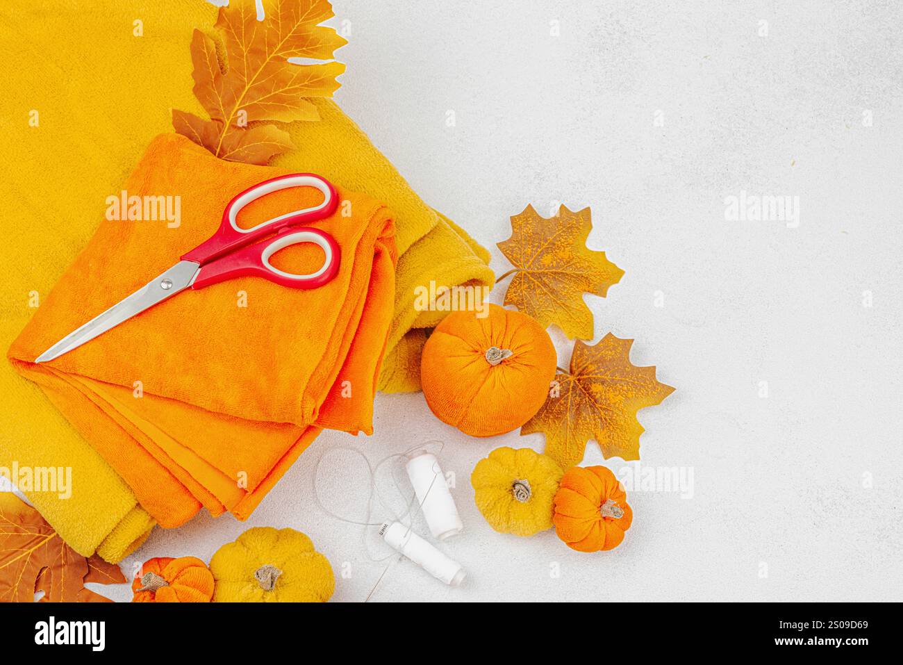 Il concetto di artigianato di Halloween. Zucche morbide cucite, processo creativo, strumenti e materiali professionali. Sfondo chiaro, vista dall'alto Foto Stock