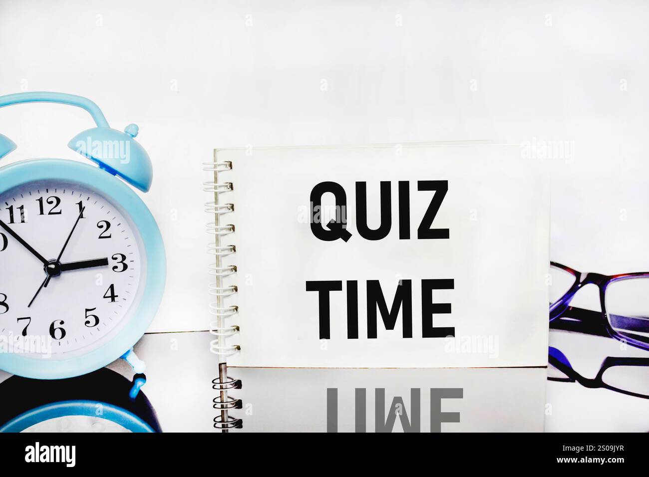 L'ora del Quiz sull'iscrizione accanto alla sveglia su sfondo bianco. il concetto di rispondere a domande o giochi a quiz. spazio di testo Foto Stock