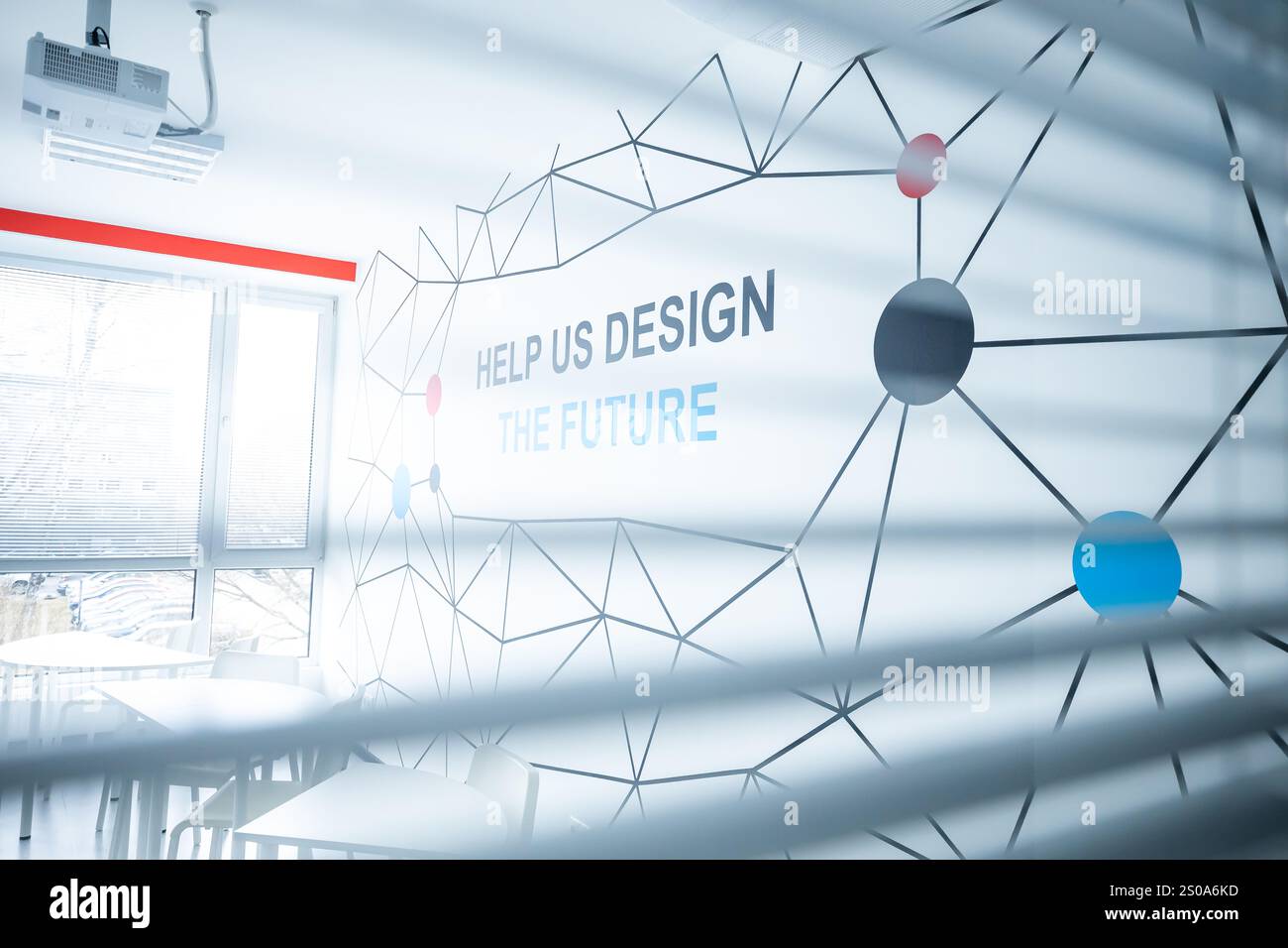 Gli interni ben illuminati presentano un design geometrico a parete con la frase "AIUTACI A PROGETTARE IL FUTURO". La luce naturale e le ombre creano un AT dinamico Foto Stock