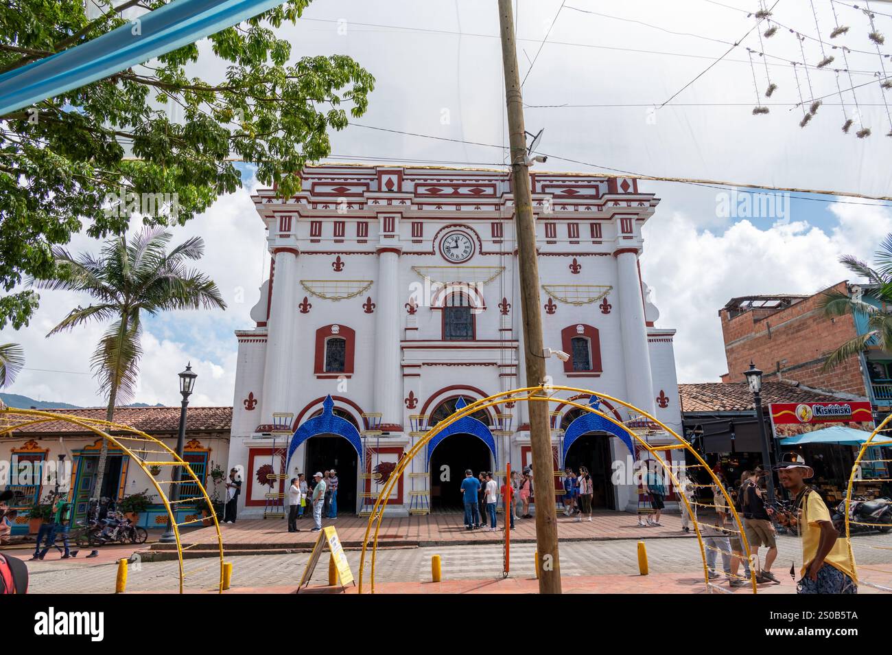 Vivace piazza cittadina con una suggestiva chiesa coloniale come suo fulcro. Una vivace scena di comunità e cultura. Foto Stock