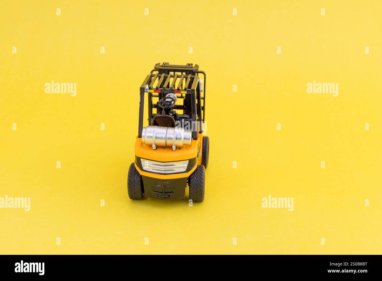Vista posteriore di un carrello elevatore giocattolo giallo su sfondo giallo con spazio vuoto per il testo. Foto Stock