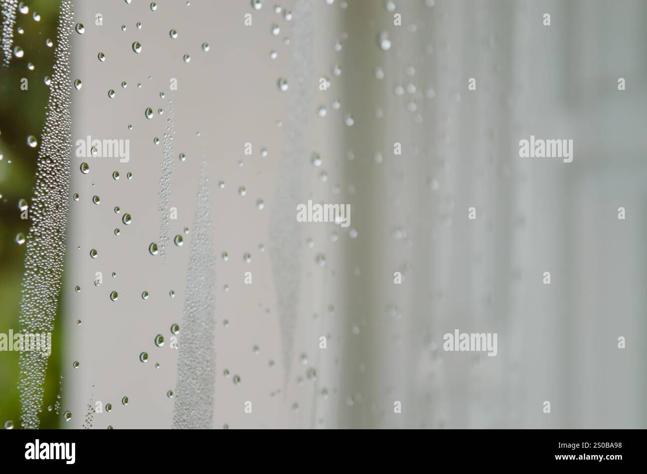 gocce di pioggia durante la giornata piovosa vetri esterni con sfondo sfocato e goccioline d'acqua che scorrono lungo la superficie Foto Stock