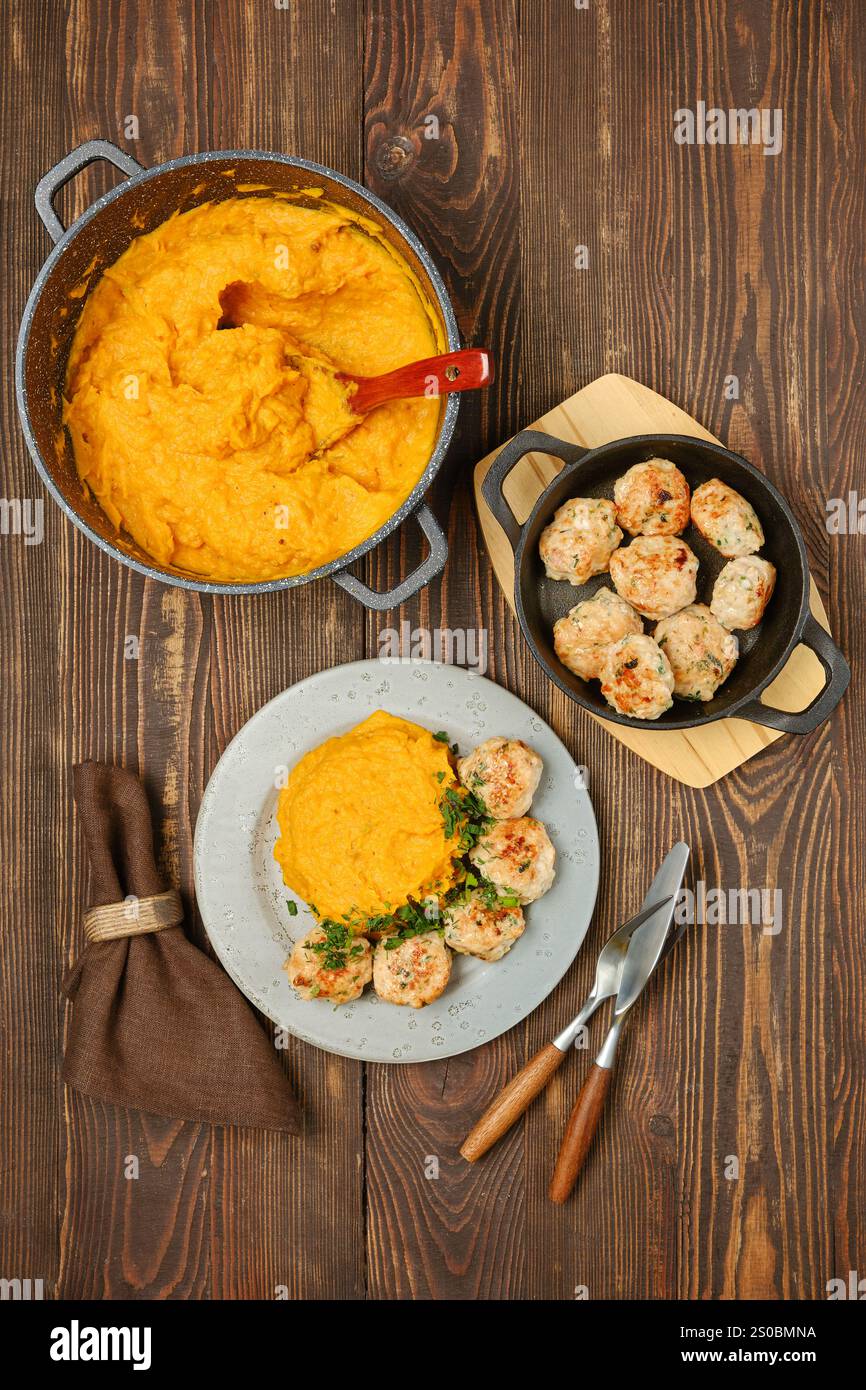 Un pasto sostanzioso con crema di zucca e polpette di tacchino, elegantemente placcate su un rustico tavolo in legno, vista dall'alto Foto Stock