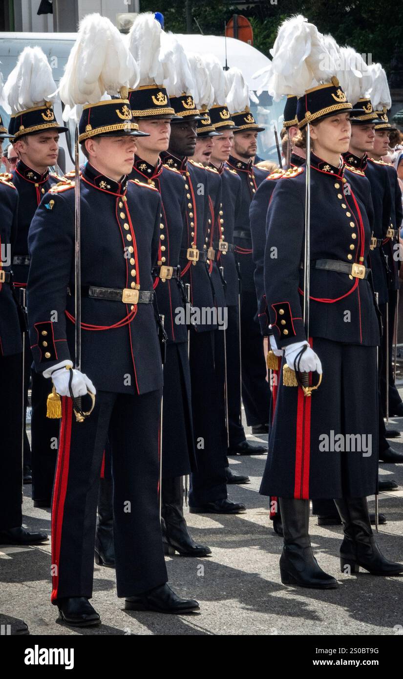 Un gruppo di soldati in uniforme in piedi in formazione durante un evento cerimoniale. Indossano uniformi militari blu scuro con accenti dorati e alte feathe Foto Stock