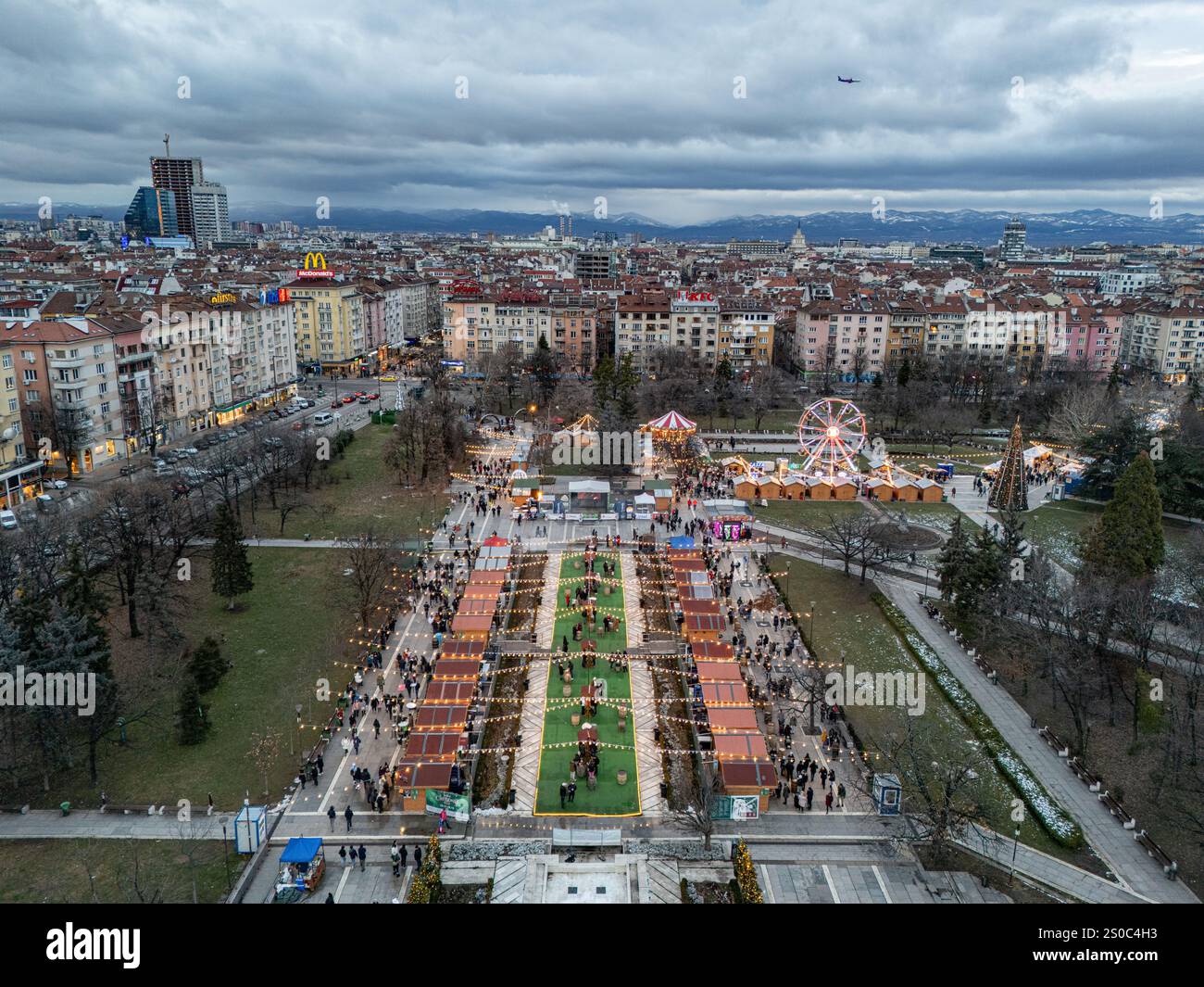 Una vibrante vista aerea del mercato di Natale di Sofia vicino al Palazzo Nazionale della Cultura (NDK). Luci festive, ruota panoramica e fascino invernale. Foto Stock