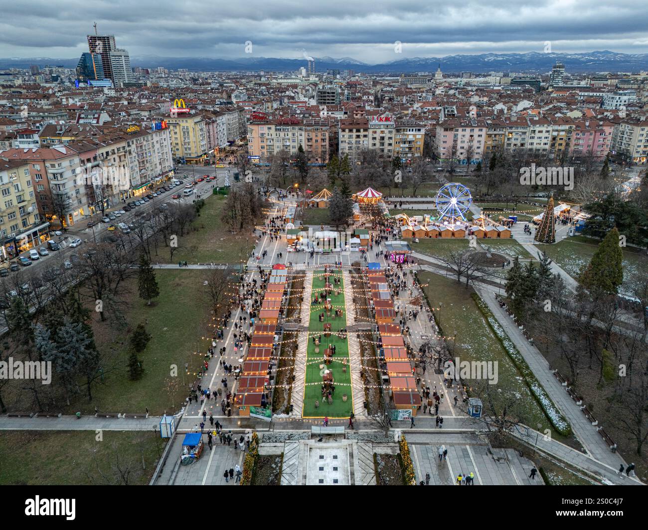 Una vibrante vista aerea del mercato di Natale di Sofia vicino al Palazzo Nazionale della Cultura (NDK). Luci festive, ruota panoramica e fascino invernale. Foto Stock
