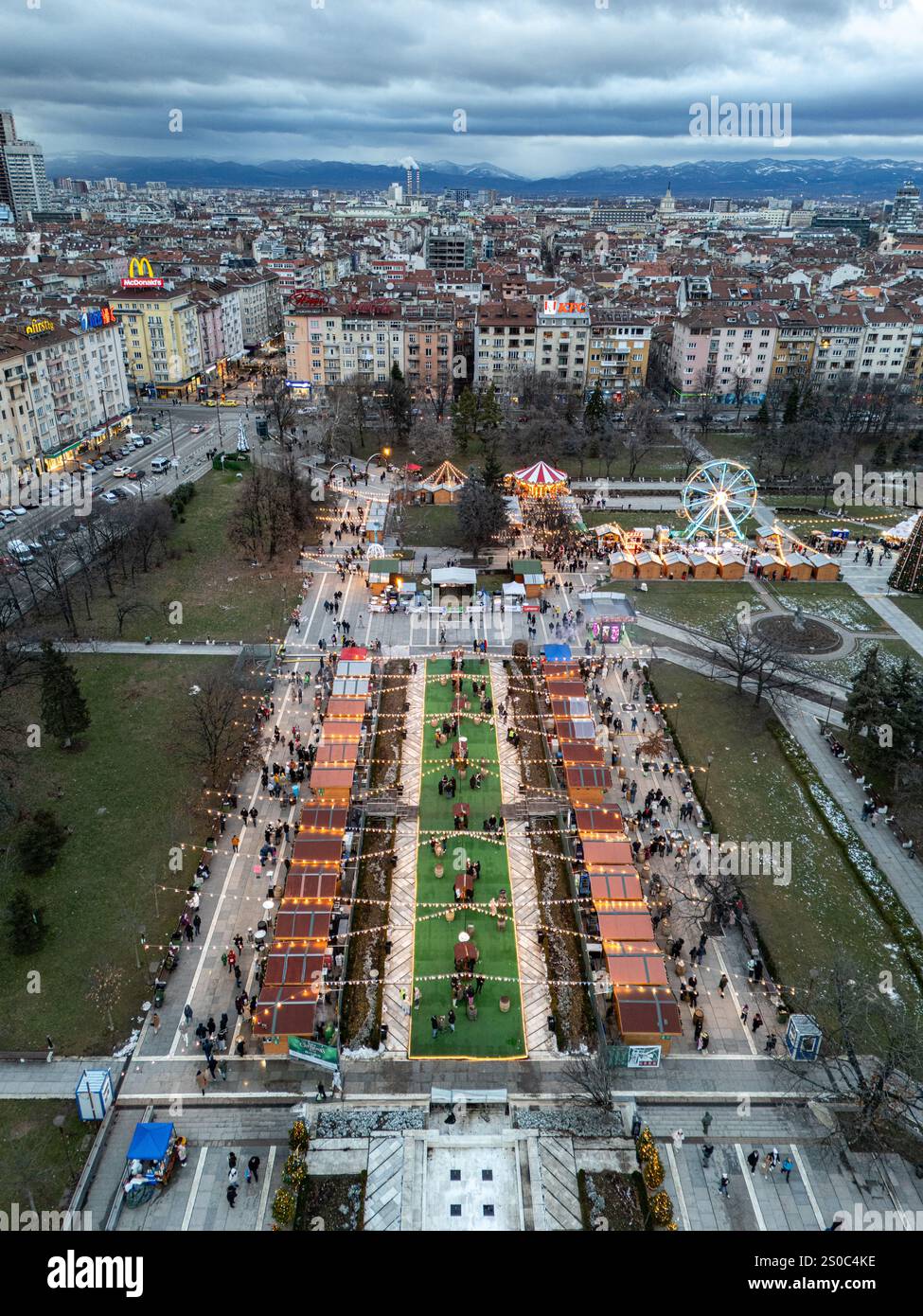 Una vibrante vista aerea del mercato di Natale di Sofia vicino al Palazzo Nazionale della Cultura (NDK). Luci festive, ruota panoramica e fascino invernale. Foto Stock