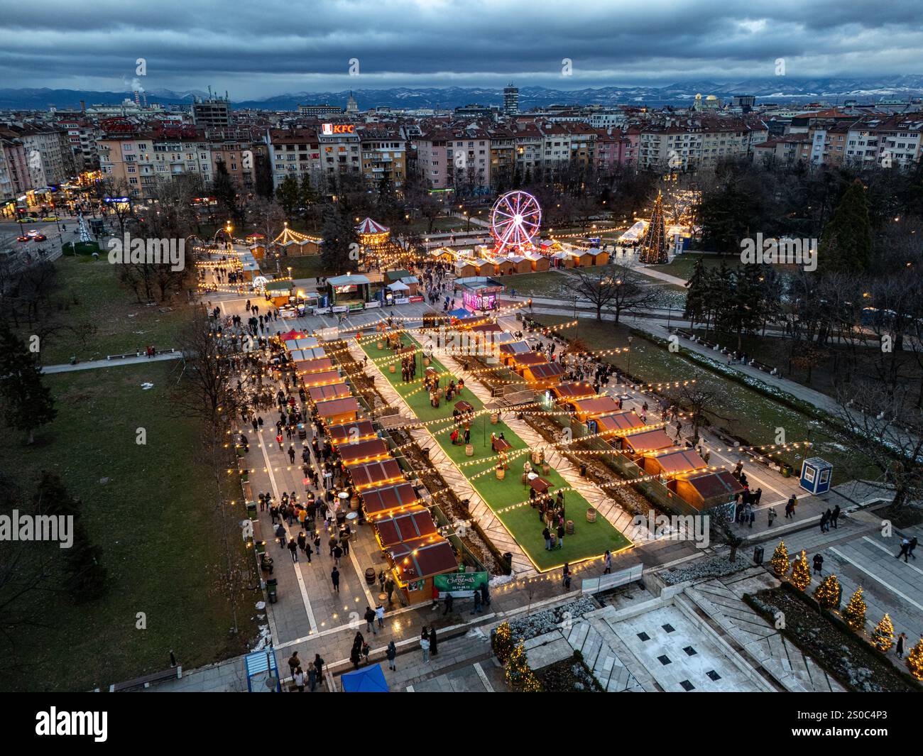 Un'affascinante vista aerea del mercato di Natale di Sofia al crepuscolo, vicino a NDK, con luci vivaci, bancarelle festose, una ruota panoramica, e festeggiamenti natalizi. Foto Stock