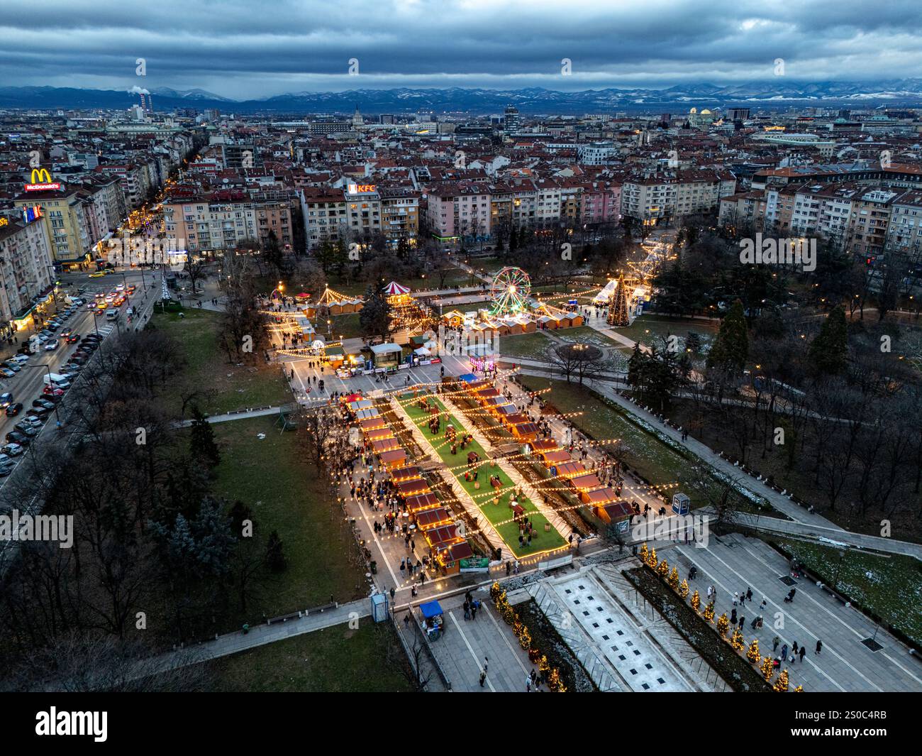 Un'affascinante vista aerea del mercato di Natale di Sofia al crepuscolo, vicino a NDK, con luci vivaci, bancarelle festose, una ruota panoramica, e festeggiamenti natalizi. Foto Stock