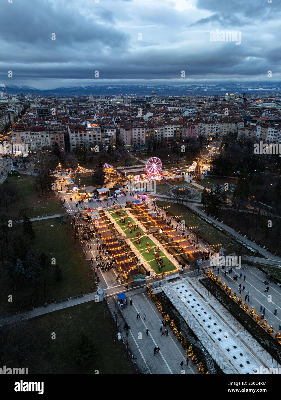 Un'affascinante vista aerea del mercato di Natale di Sofia al crepuscolo, vicino a NDK, con luci vivaci, bancarelle festose, una ruota panoramica, e festeggiamenti natalizi. Foto Stock