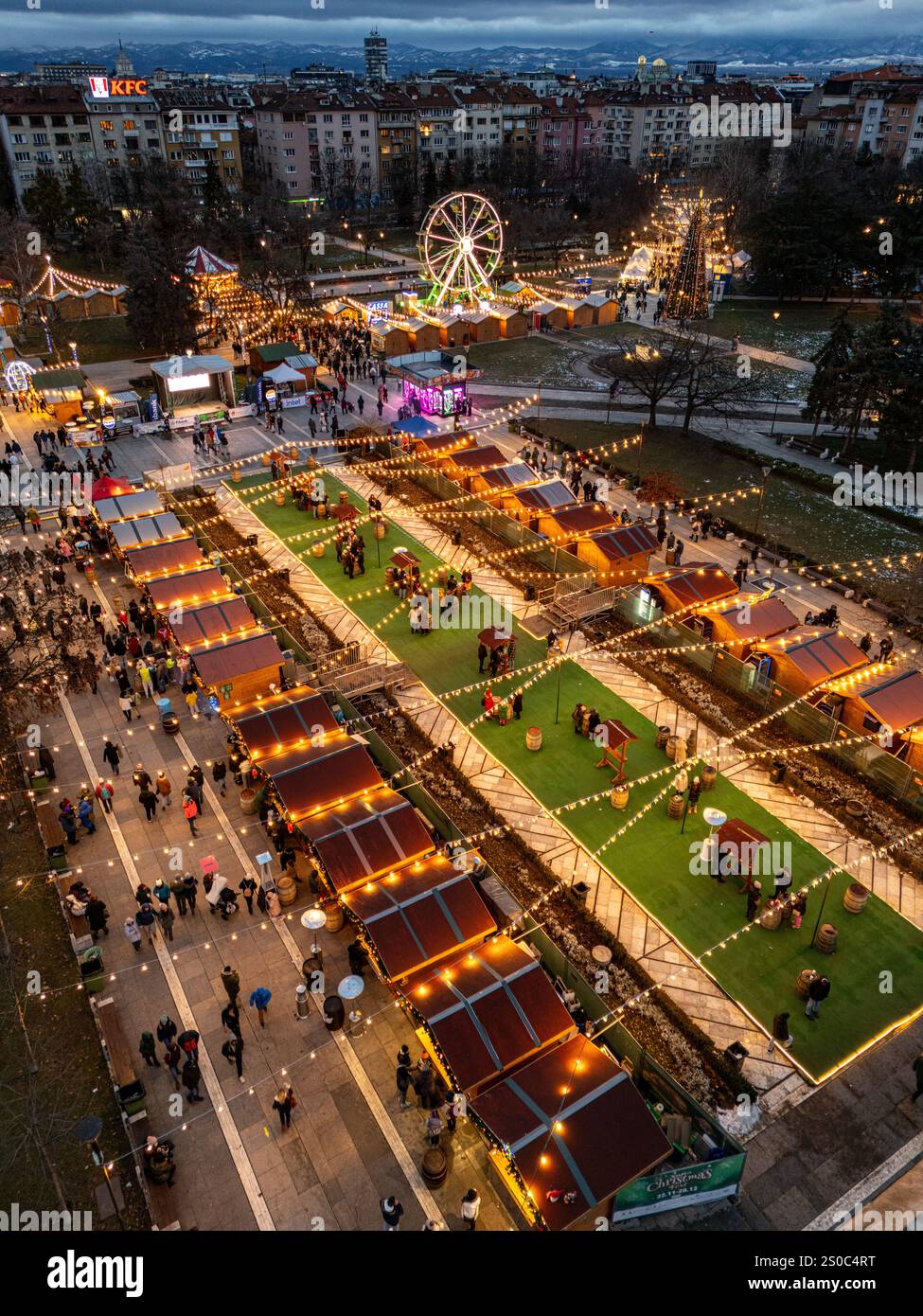 Un'affascinante vista aerea del mercato di Natale di Sofia al crepuscolo, vicino a NDK, con luci vivaci, bancarelle festose, una ruota panoramica, e festeggiamenti natalizi. Foto Stock