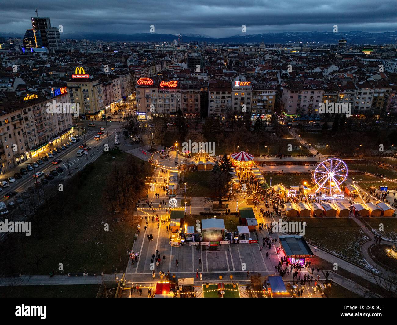 Un'affascinante vista aerea del mercato di Natale di Sofia al crepuscolo, vicino a NDK, con luci vivaci, bancarelle festose, una ruota panoramica, e festeggiamenti natalizi. Foto Stock