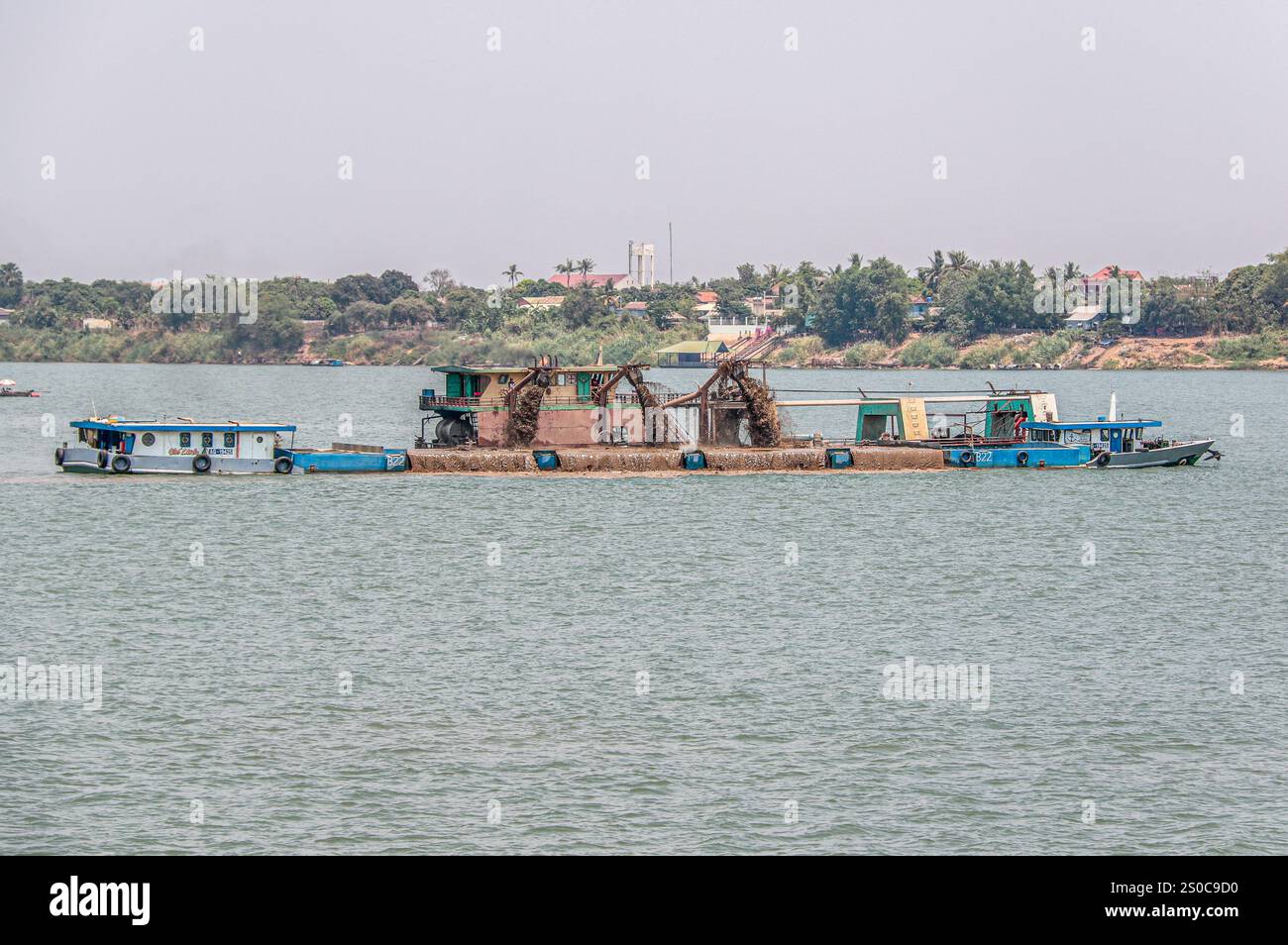 Mekong Delta, Vietnam. 27 dicembre 2024: Piattaforma di dragaggio draga il canale e carica navi/chiatte da carico. L'estrazione di sabbia e ghiaia (miniere o draghe) utilizzata per il calcestruzzo nell'industria edile solleva avvertenze circa l'impatto ambientale del sovrasfruttamento dei sedimenti del letto dei fiumi (biodiversità ed ecosistema), ma anche sulla vita delle persone che vivono sulle rive dei fiumi. Lo sfruttamento legale o illegale della sabbia provoca una massiccia erosione delle banche, con conseguente perdita di terreni agricoli, ma anche il crollo di edifici e case e lo spostamento delle popolazioni. Crediti: KEVIN IZORCE/Alamy Live News Foto Stock