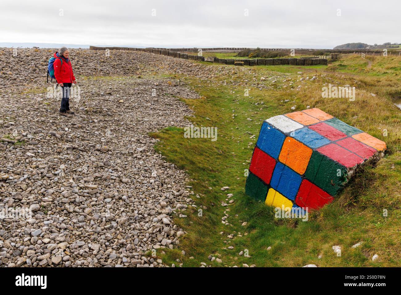 Persona che guarda un cubo di Rubik dipinto sulle difese costiere della seconda guerra mondiale, Limpert Bay, Aberthaw, Galles, Regno Unito Foto Stock