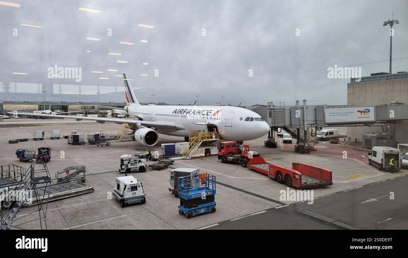 Aeroporto Charles de Gaule un Airbus A330 dell'Air France parcheggiato al cancello, con equipaggio di terra che lavora attivamente per caricare il carico e preparare l'aereo - Immagine stock catturata con smartphone
