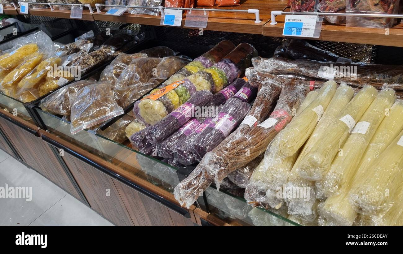 Un'esposizione di vari alimenti secchi in imballaggi trasparenti, tra cui spaghetti, verdure conservate ed erbe aromatiche, disposti ordinatamente in un negozio di alimentari. Foto Stock