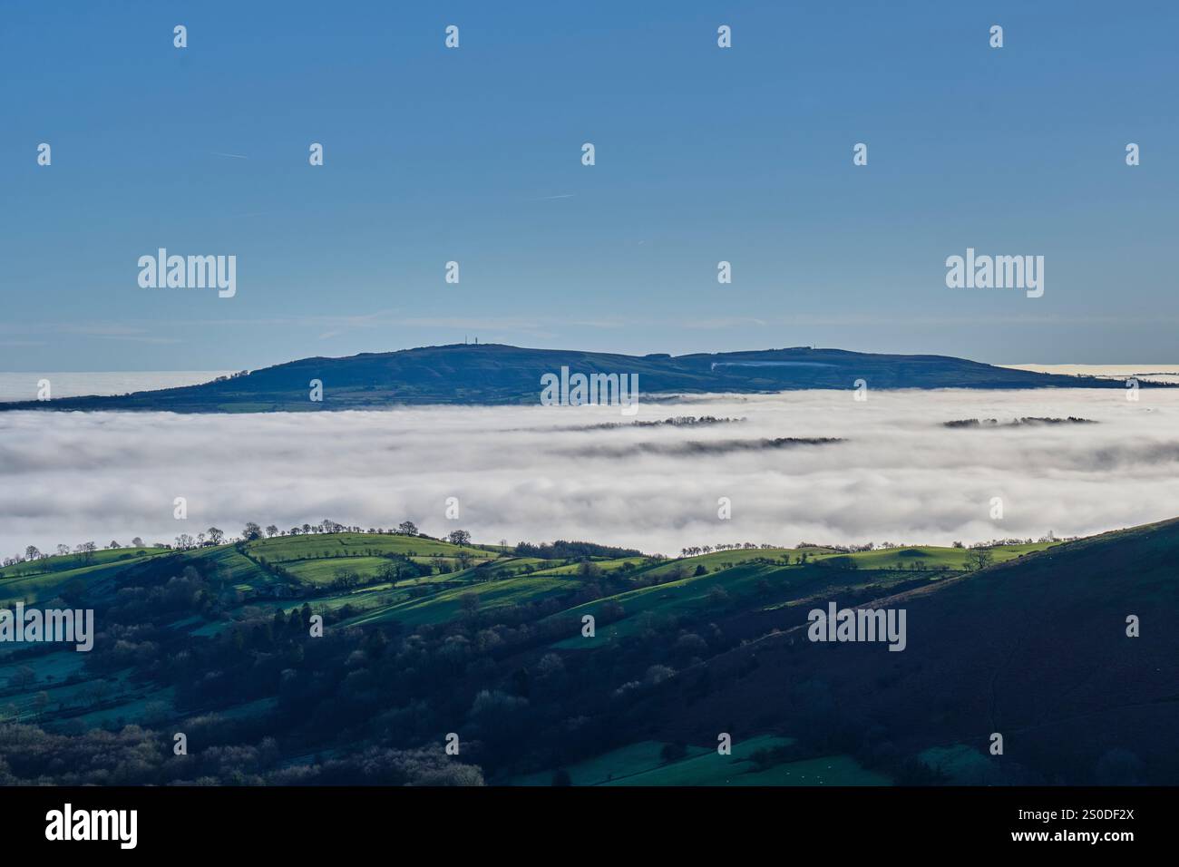 Brown Clee Hill che si insinua nella bassa nebbia e nebbia di un'inversione, vista da Caer Caradoc, Church Stretton, Shropshire Foto Stock