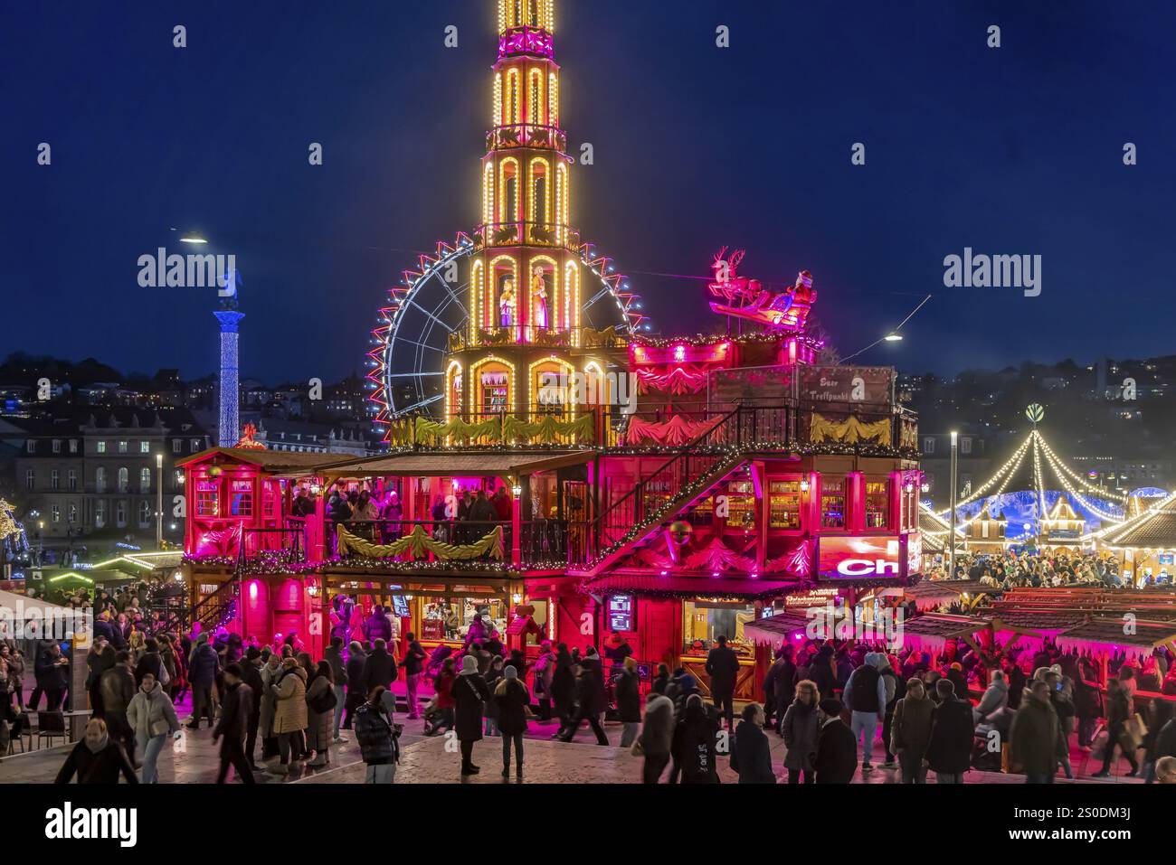 Mercatino di Natale di Stoccarda all'ora blu. Piramide di Natale su Schlossplatz di fronte al Palazzo nuovo con ruota panoramica. L'evento tradizionale Foto Stock