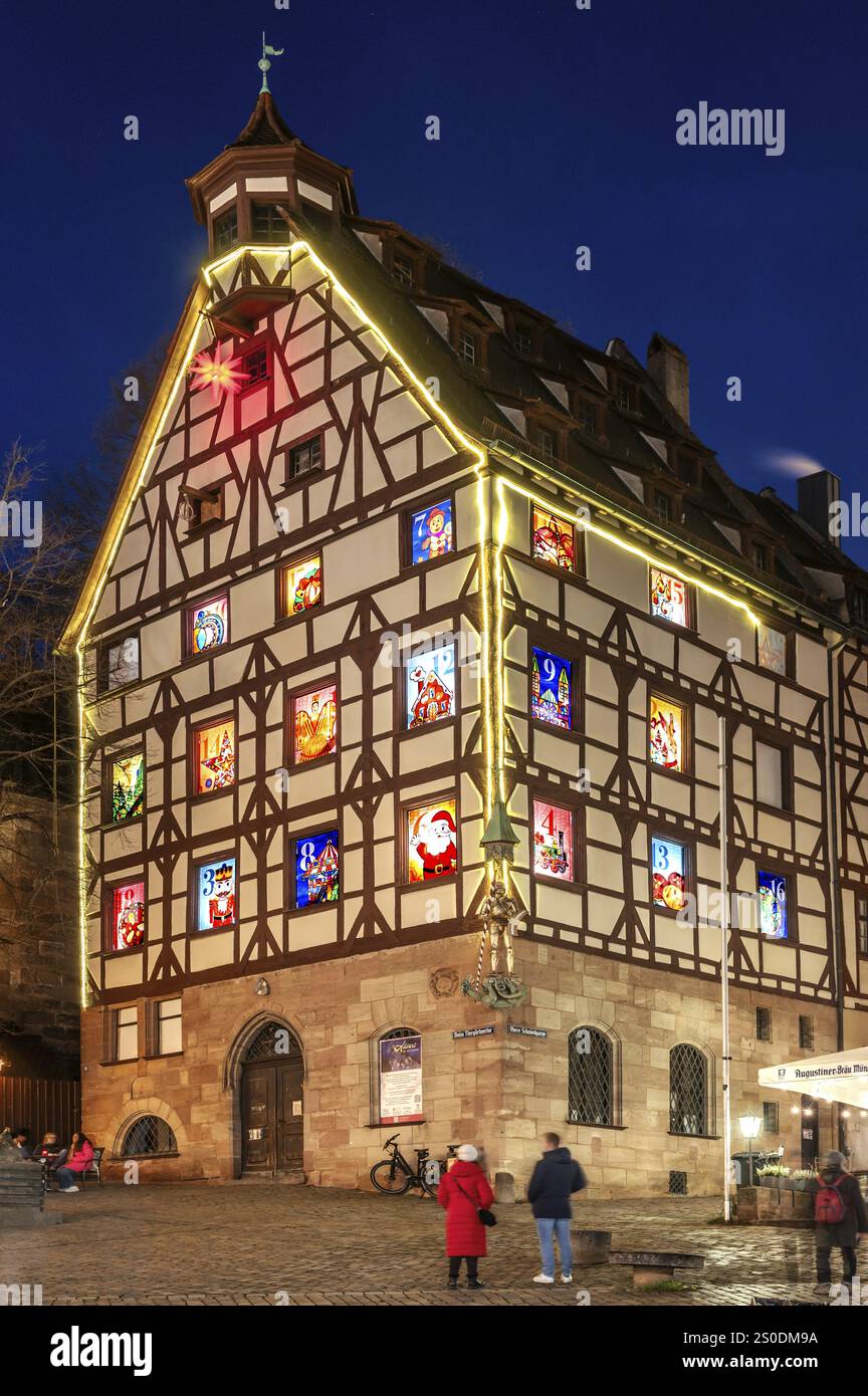 Pilatushaus, costruito nel 1489, una storica casa cittadina con un calendario dell'Avvento il 18 dicembre 2024 al crepuscolo, il Castello Imperiale sulla destra, Tiergaertnert Foto Stock