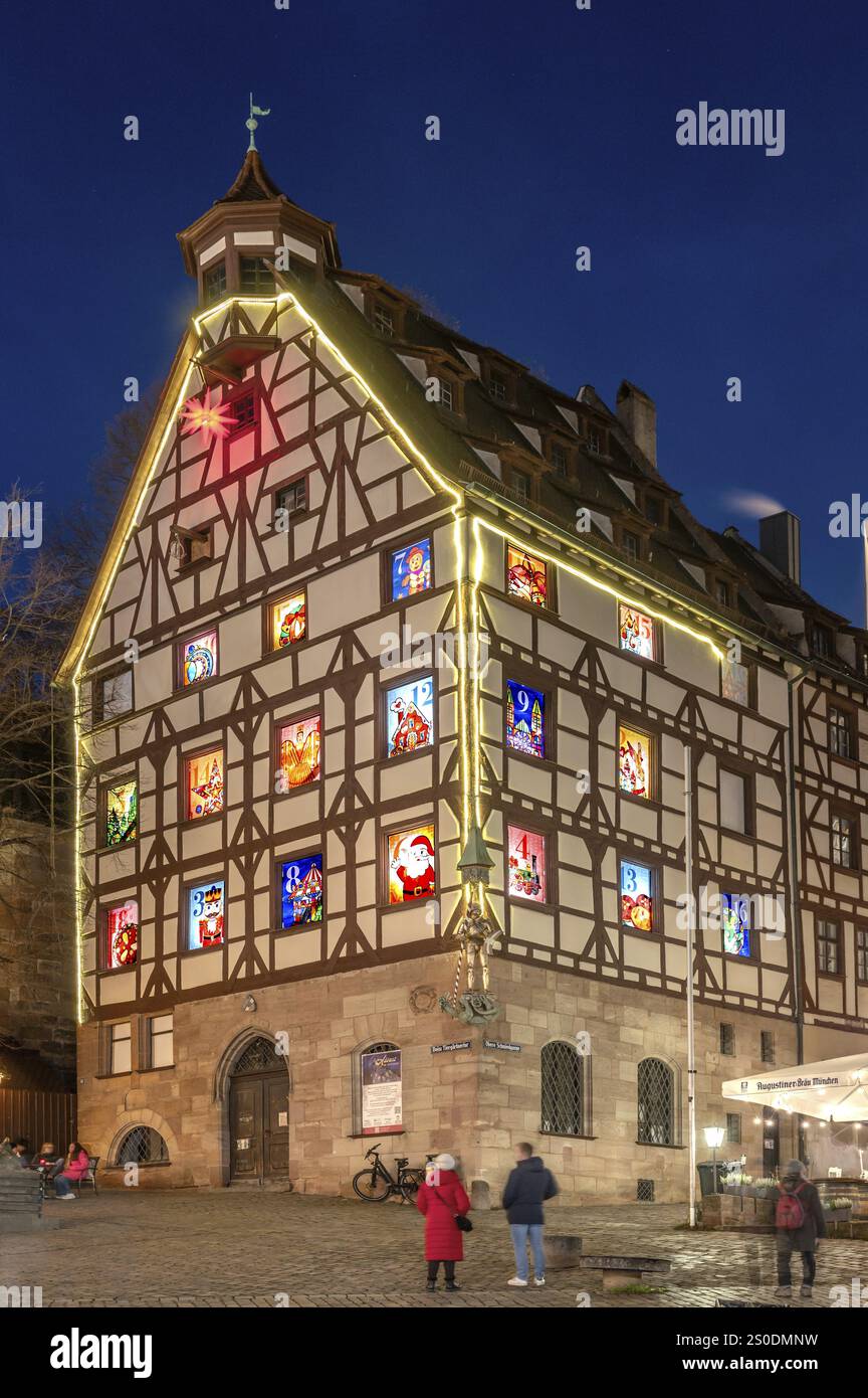 Pilatushaus, costruito nel 1489, una storica casa cittadina con un calendario dell'Avvento il 18 dicembre 2024 al crepuscolo, il Castello Imperiale sulla destra, Tiergaertnert Foto Stock